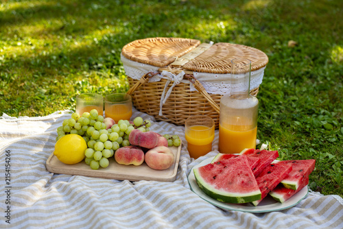 Fotografía Summer Picnic Basket with Fresh Fruit and Orange Juice in Green Garden