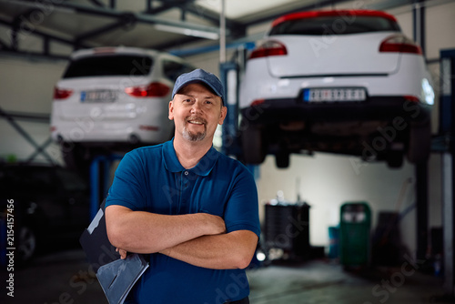 Portrait of confident mature mechanic in car workshop looking at camera.