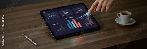 technology and busingess theme background Person analyzing business dashboard on tablet with coffee on wooden table