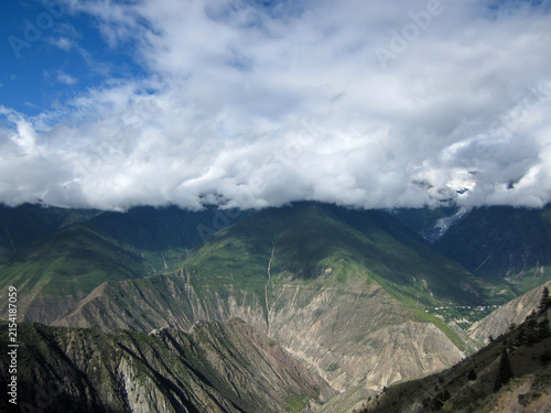 Quadro su tela Breathtaking mountain range with clouds covering the peaks under a blue sky