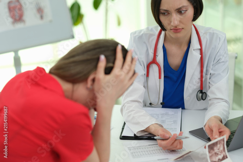 Woman cries as doctor explains ultrasound images bad meaning in clinic. Female physician shows support to despaired patient at appointment in hospital