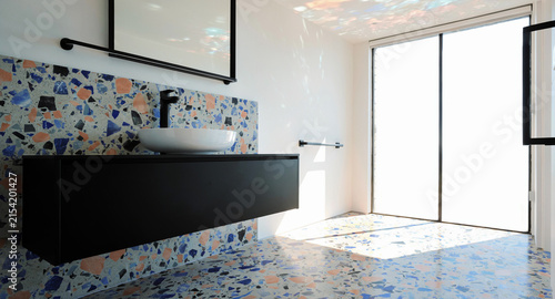 Modern minimalist bathroom interior featuring colorful terrazzo wall and floor tiles with natural sunlight with showcases contemporary bathroom