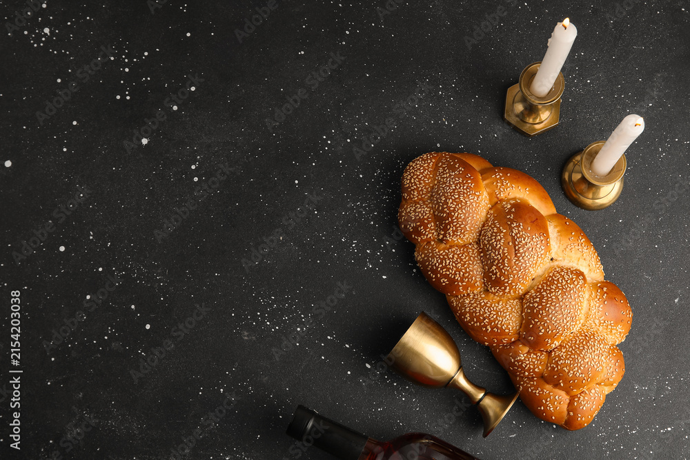 Fototapeta premium Traditional challah bread with wine and burning candles on dark background. Shabbat Shalom