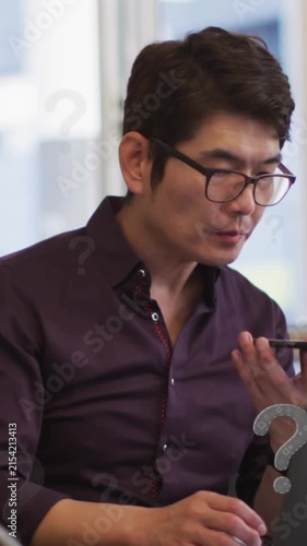 Animation of question marks over asian businessman working at office