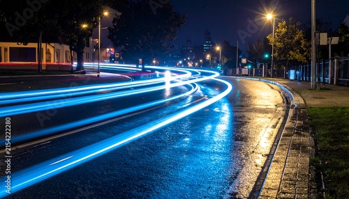 Wavy blue light trails reflecting on a dark wet city street, long exposure, abstract photography, simple composition