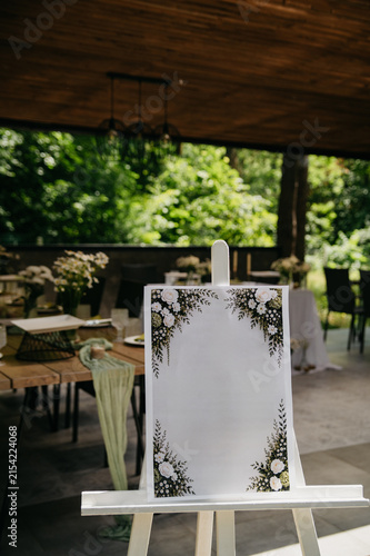 The interior of a banquet hall made of wood in the form of a gazebo in an open space with tables set with dishes, food and drinks for a wedding or anniversary celebration