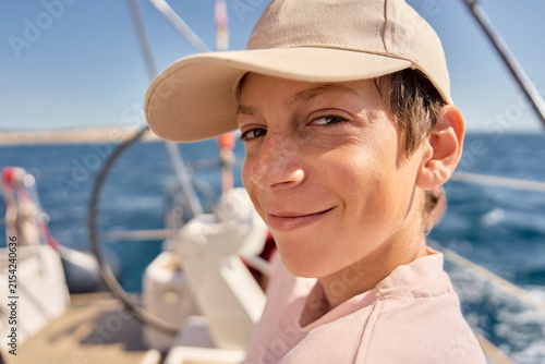 A smiling teenage boy enjoys sailing on the ocean in Croatia