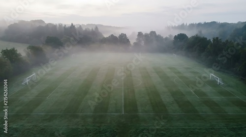 Aerial view of a striped soccer field covered in early morning fog.