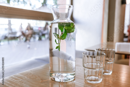 A glass carafe filled with fresh water and fresh mint leaves
