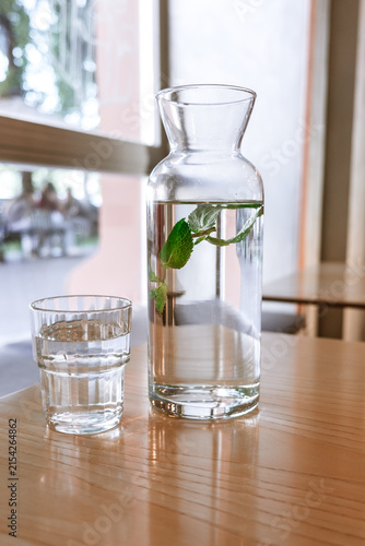 A glass carafe filled with fresh water and fresh mint leaves