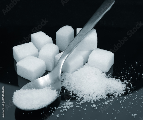 Sugar granules and cubes with a metal spoon concept