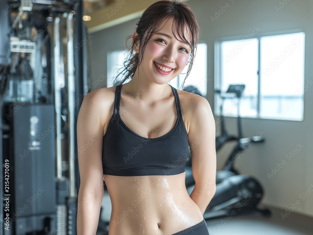 Fototapeta premium ジムでトレーニングを終えて爽やかな笑顔を浮かべ汗を流すスポーツウェア姿の若い女性