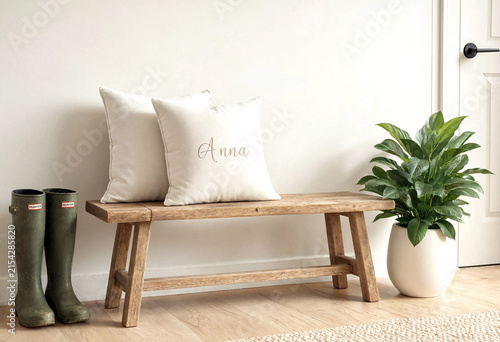 Cozy wooden bench with cushions and green rain boots beside a potted plant in modern home entryway decor