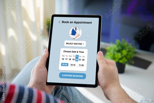 Man holding tablet with medical doctor appointment booking app interface