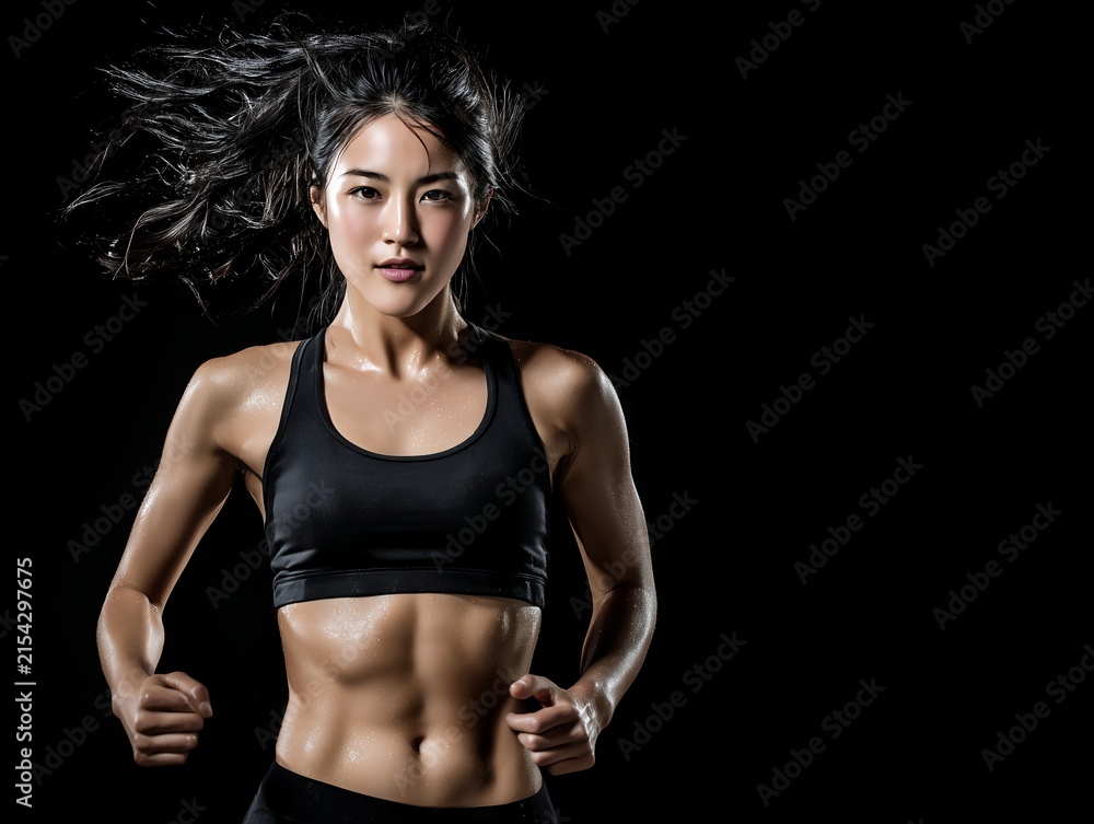Obraz premium 腹筋の割れたスポーティーな女性が黒背景の前で汗を流しながら力強く走るフィットネス