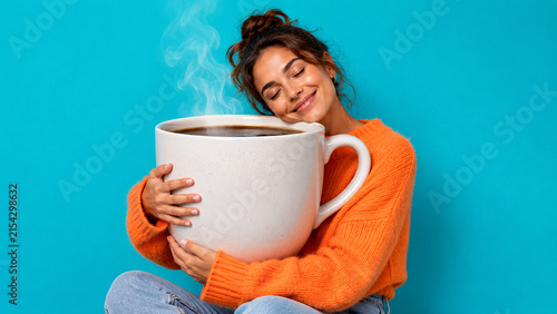 Happy woman hugging giant coffee mug as comfort, warmth and morning energy concept