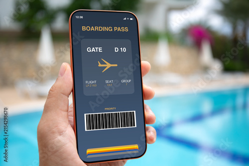 Man hand hold phone with digital boarding pass pool background