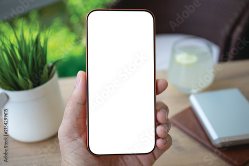 Man hand holding phone blank white screen mockup office desk