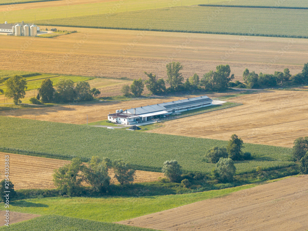 Fototapeta premium Farmland aerial view with modern farm building and silos showing agriculture development