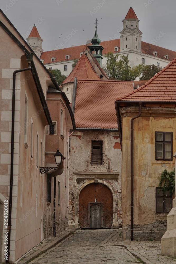 Obraz premium Historic narrow cobblestone street leading to a view of the famous Bratislava Castle in the old town, Slovakia