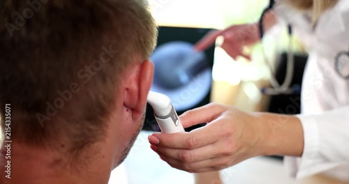 A skilled healthcare professional carefully looks into a patient s ear using a specialized device while discussing findings in a sunny clinic.
