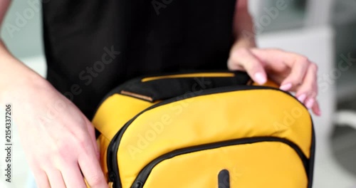 A person skillfully organizes their belongings inside a bright yellow backpack in a modern setting. The atmosphere feels fresh and energetic as they prepare for an adventure.