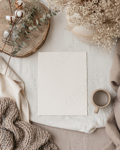 overhead editorial photography of a beautiful neutral-toned styled tabletop, a single blank A4 art print sheet lying completely flat and unobstructed in the centre