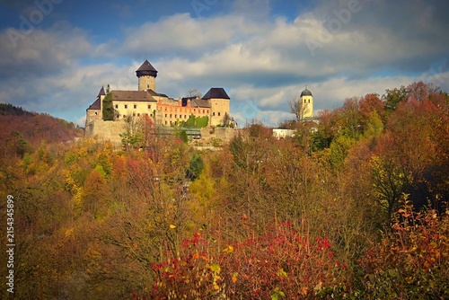 Medieval Sovinec Castle surrounded by colorful autumn forest under a cloudy sky, Czech Republic.