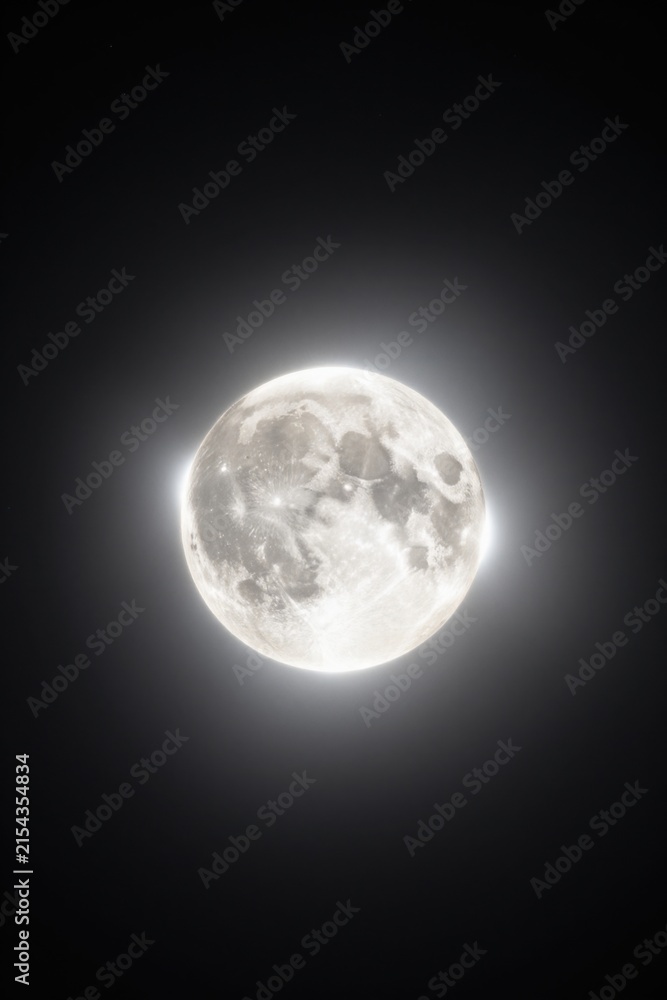 Obraz premium Full moon glowing brightly with a visible lunar surface set against a dark night sky background. Bright full moon with detailed craters and surface texture surrounded by a soft glowing white aura.