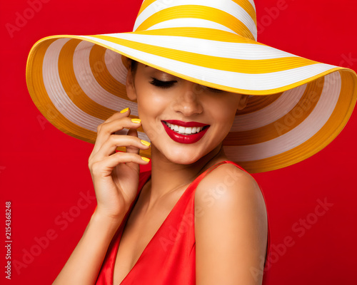 Beautiful Woman Smiling in Large Striped Sun Hat and Red Dress.