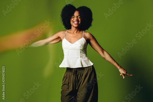 Woman dances with smiling energy in a green background studio portrait