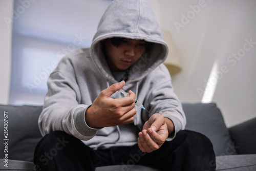 Photography Young Man in Hoodie Holds Syringe, Illustrating Concepts of Drug Addiction and S