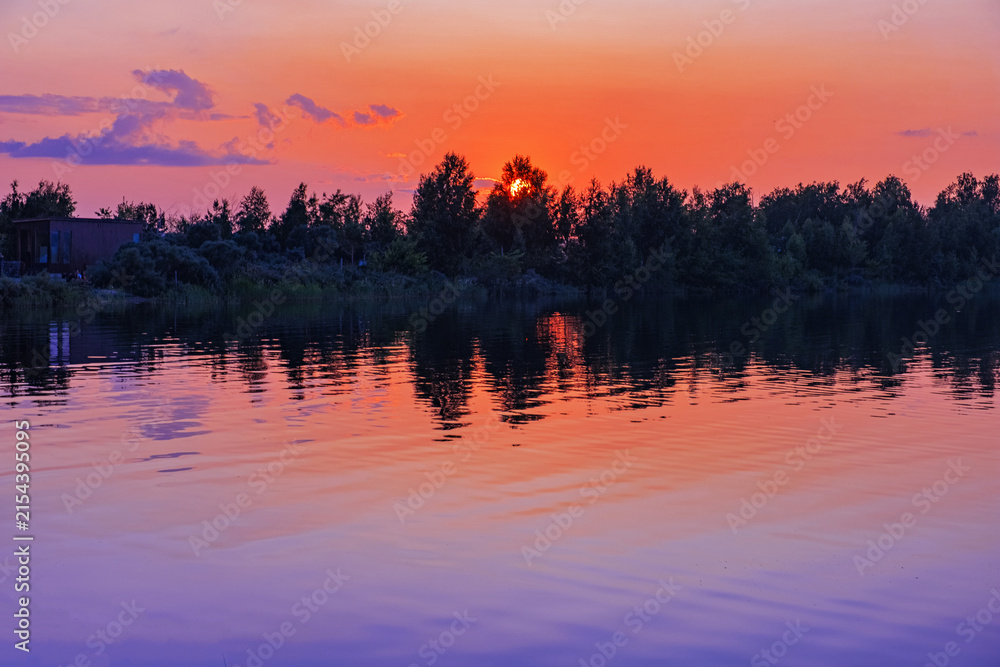 Obraz premium Beautiful sunset over Ulken Shabakty lake in Kazakhstan. Rd blue gradient sky with colored clouds and ripples on calm water. Serene twilight lake pastel color landscape. Dreamy romance evening.