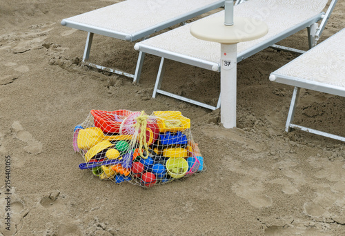 a net bag of children beach toys beside sunbeds