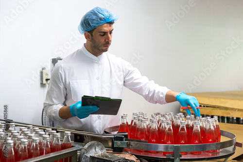 Portrait of mature male researcher with bottle of red beverage in bottle factory.
