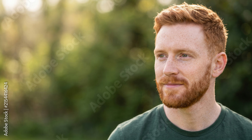 Thoughtful Redheaded Man With Freckles Outdoors in Warm Sunlight