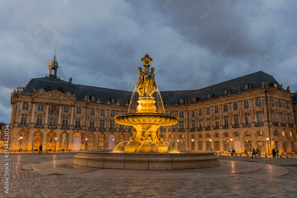 Obraz premium Beleuchteter Brunnen der Drei Grazien am Place de la Bourse, Bordeaux, Frankreich