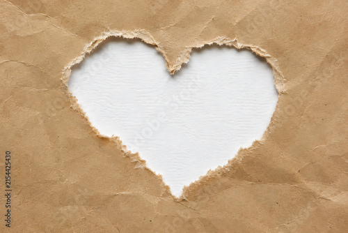 Crumpled brown paper heart frame, torn kraft paper hole on white background, rustic recycled paper texture for romantic greeting cards