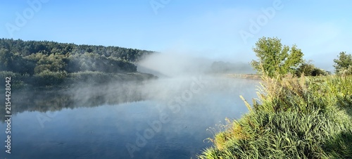 Morning fog over the Dnieper River, a beautiful summer landscape with a blue sky.
