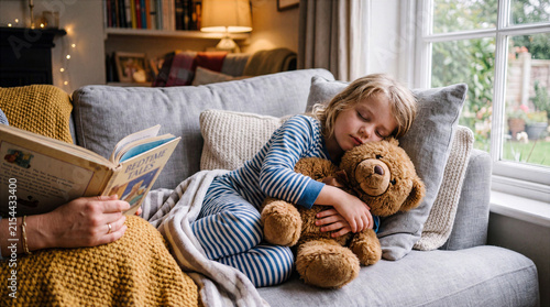 Little girl sleeping peacefully hugging teddy bear while mother reads bedtime story