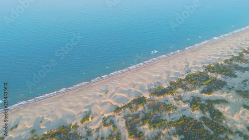 Gelemis, Turkey. Patara Beach, an 18-kilometer stretch of golden sand dunes and coastal shrubs, aerial view in warm morning light with long shadows stretching toward the Mediterranean horizon. Aerial