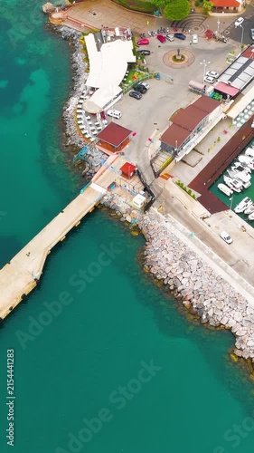 Vertical video. Alanya, Turkey. Kizilkule Red Tower, an octagonal Seljuk fortress of red brick and limestone, rises 33 meters above the harbor in a sweeping aerial view over the turquoise Mediterrane