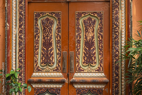 old wooden door decorated with carved floral ornament in oriental style. antique door panels with arabesque pattern and plant motifs. concept of door craft and traditional carving art in architecture