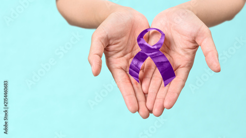 Konstfotografi Close-up of open hands gently holding a purple awareness ribbon against a light blue background