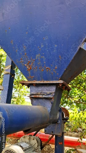Weathered Industrial Machinery Detail: Rusted Blue Metal Hopper and Conveyor Pipe with Peeling Paint