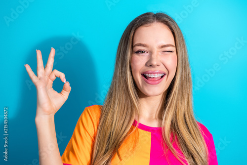 Фотография Smiling young woman winking and ok gesture in bright pink and orange shirt again