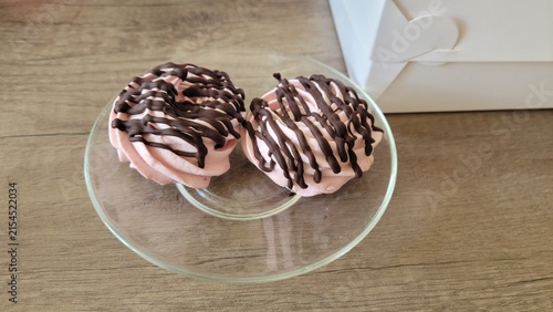 Two pink marshmallow desserts topped with chocolate drizzle on glass plate
