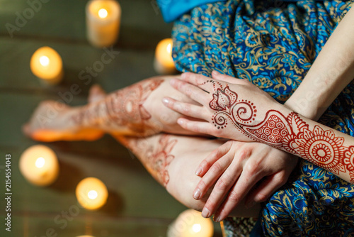 A close-up shot captures a person with intricate henna tattoos