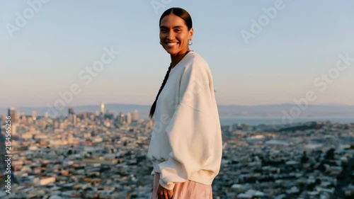 Woman standing overlooking city skyline at sunset in oversized sweater for urban portrait background and lifestyle banner design