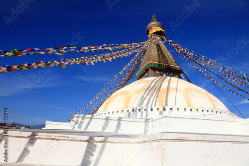 Boudhanath Stupa decorated with colorful Buddhist prayer flags against a deep blue sky in Kathmandu, Nepal